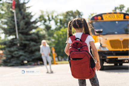 Child with a red backpack walking toward a school bus on the first day of school, illustrating how a separation agreement attorney in Fairfax can help parents address school schedules, transportation, and parenting responsibilities before the new school year.